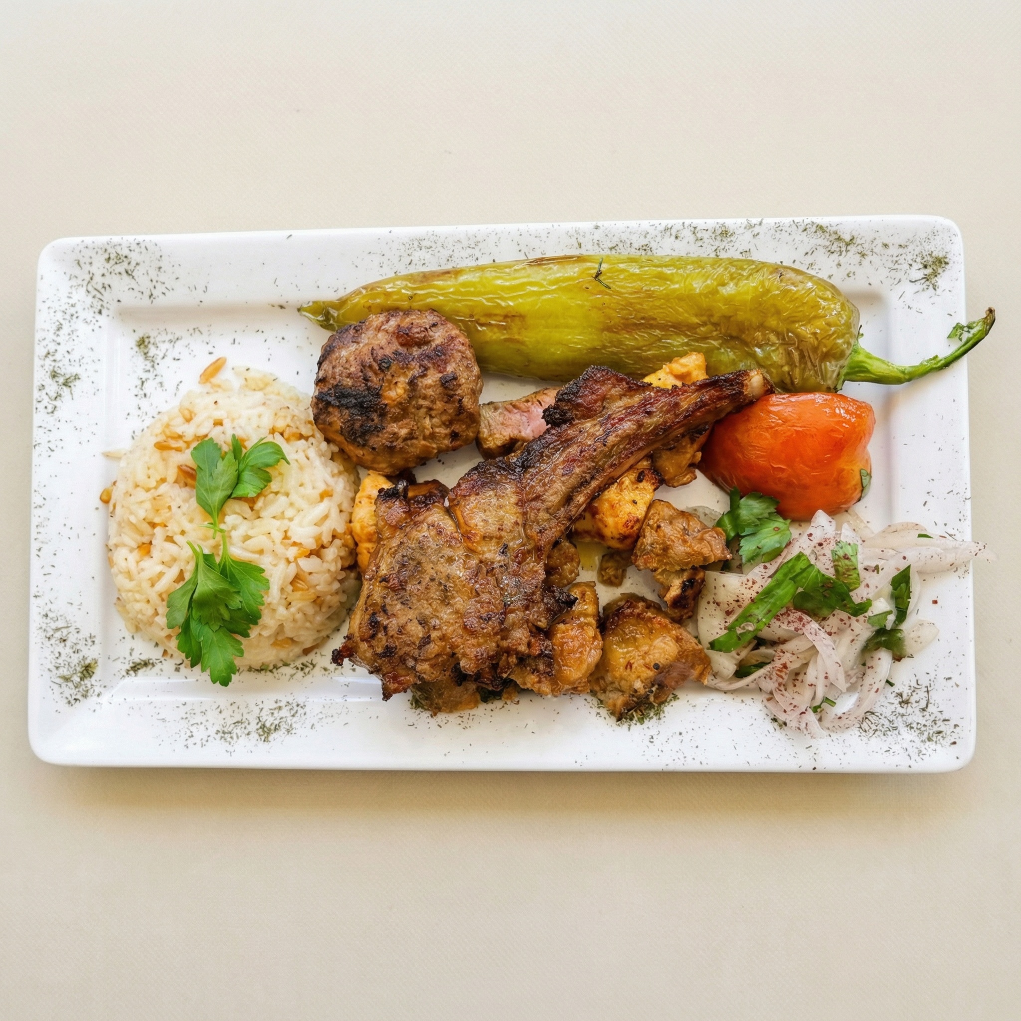 Gemischter türkischer Grillteller mit Lammkotelett, Köfte, Reisbeilage, gegrillter Paprika und Zwiebelsalat.