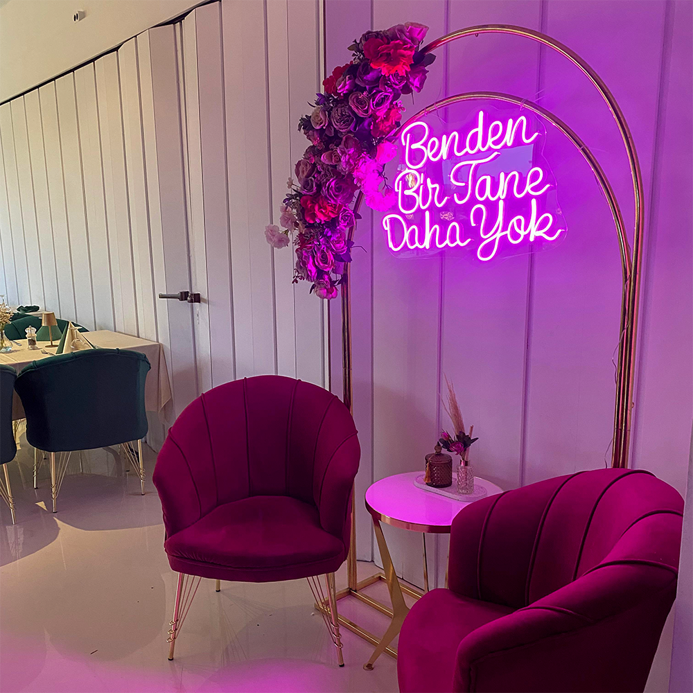 Pinke Samtsessel vor einem goldenen Bogen mit türkischer Neon-Aufschrift "Benden Bir Tane Daha Yok".