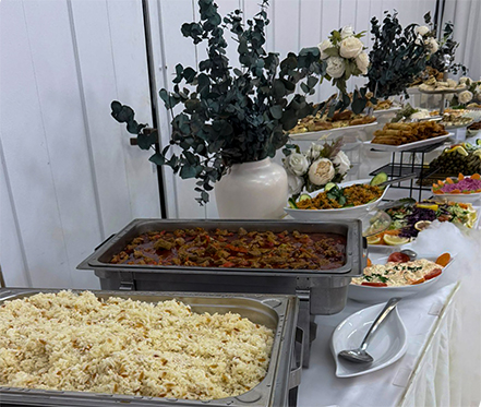 Lange Buffet-Tafel in einem weiß dekorierten Festsaal mit Blumenvasen, Eukalyptus-Zweigen und einer großen Auswahl an türkischen Gerichten.