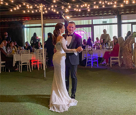 Brautpaar tanzt den Hochzeitstanz im Freien unter einer romantischen Lichterkette bei Nacht.