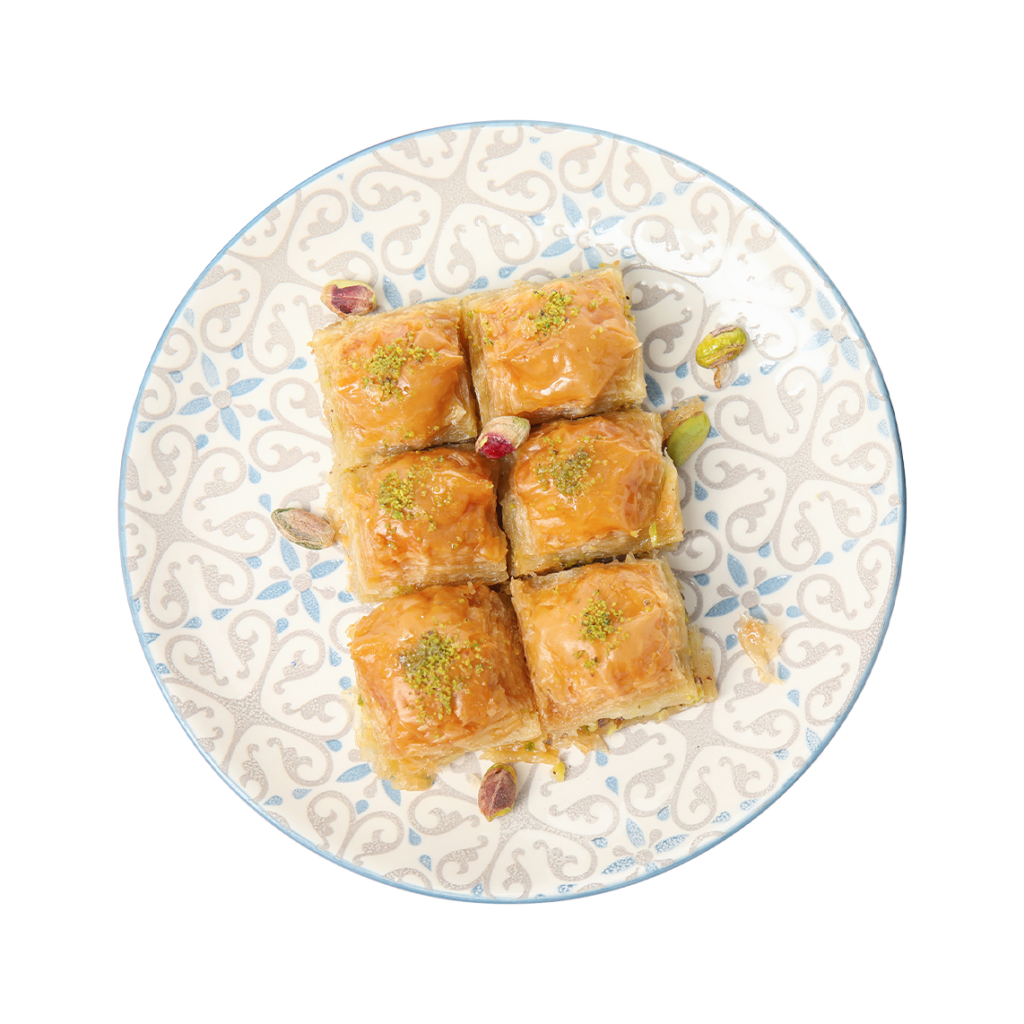 Ein gemusterter orientalischer Teller mit sechs Stücken goldbraunem Baklava, bestreut mit gehackten Pistazien und dekoriert mit ganzen Pistazienkernen.